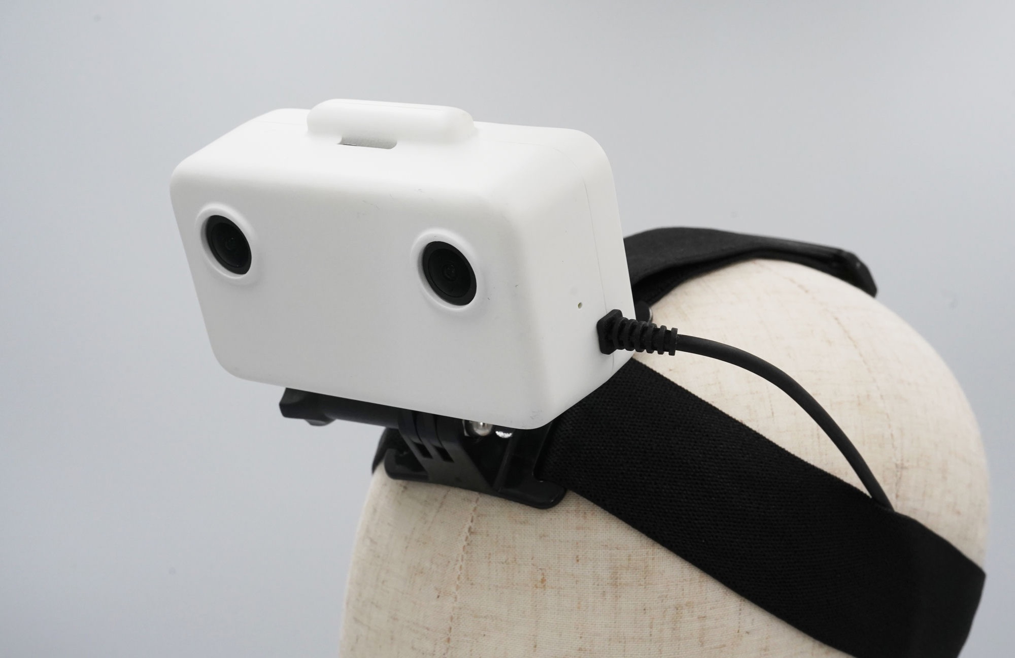 GI Ego1 worn on a head, three-quarter view showing the stereo camera module, strap, and GoPro-compatible mount